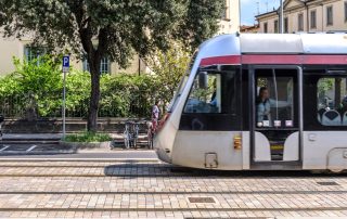Pavimentazione in pietra con binari integrati, su cui transita un tram.