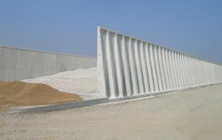 Vista laterale di un silo agricolo con pareti in cemento armato prefabbricate. La struttura presenta rinforzi verticali per garantire stabilità e resistenza alla pressione del materiale stoccato.