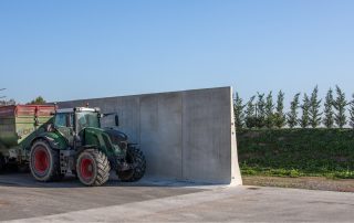 Trattore Fendt con rimorchio Casella 200 al lavoro presso un silo agricolo in cemento armato prefabbricato. Il silo presenta pareti inclinate per la massima efficienza di stoccaggio.