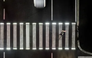 Attraversamento pedonale illuminato da luci a LED integrate nelle strisce bianche, visto dall'alto di notte.