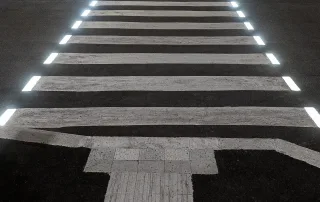 Attraversamento pedonale illuminato da luci a LED integrate nelle strisce bianche, visto dall'alto di notte.