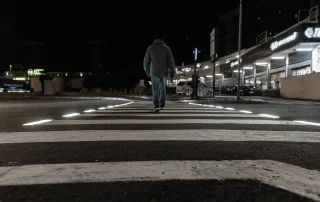Attraversamento pedonale illuminato da luci a LED integrate nelle strisce bianche, visto di notte.