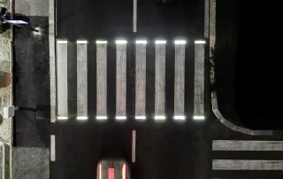 Attraversamento pedonale illuminato da luci a LED integrate nelle strisce bianche, visto dall'alto di notte.