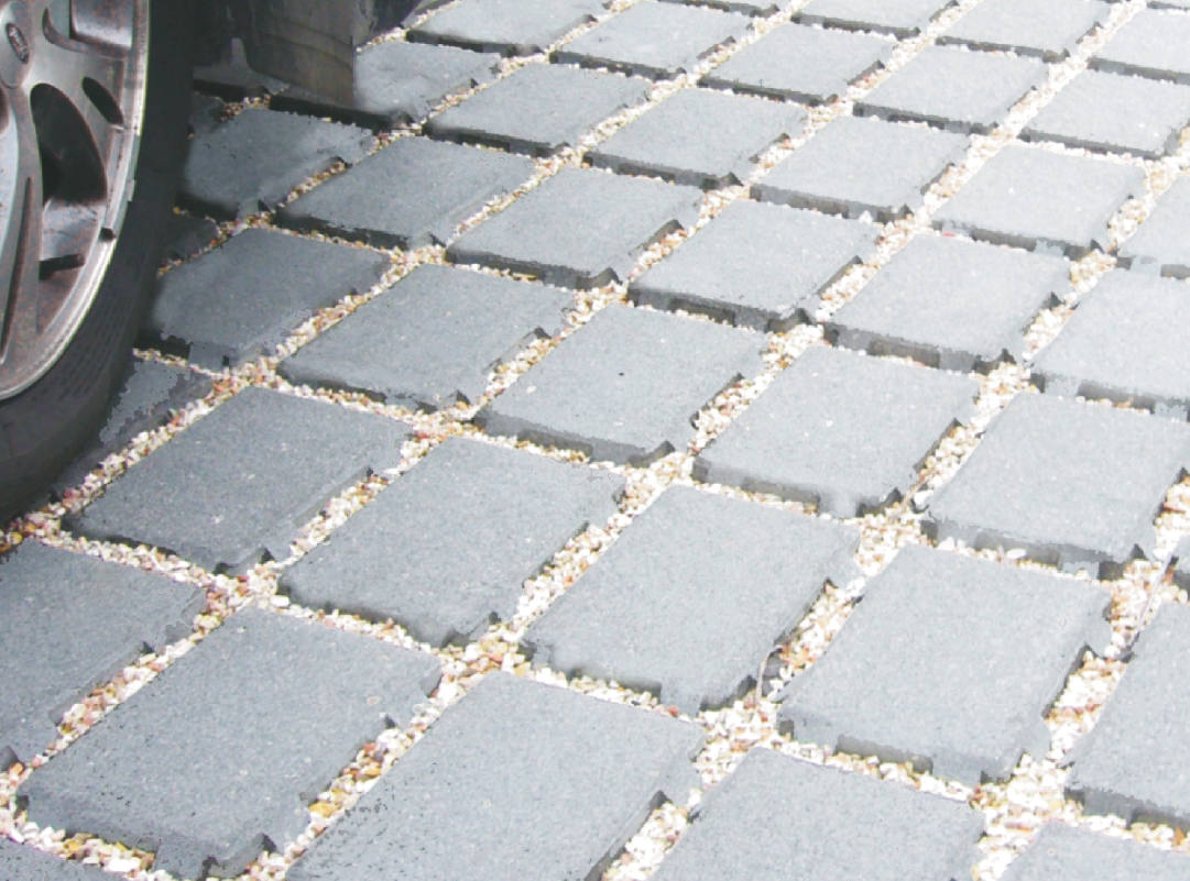 Pavimentazione drenante in calcestruzzo con elementi modulari e interspazi riempiti di ghiaia.