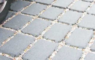 Pavimentazione drenante in calcestruzzo con elementi modulari e interspazi riempiti di ghiaia.