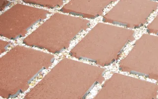 Pavimentazione drenante in calcestruzzo con elementi modulari e interspazi riempiti di ghiaia.