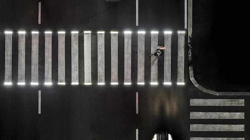 Attraversamento pedonale illuminato da luci a LED integrate nelle strisce bianche, visto dall'alto di notte.