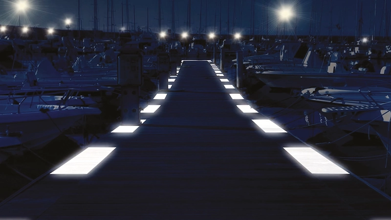 Pontile in legno illuminato da luci a LED integrate nella pavimentazione.Il molo è circondato da numerose imbarcazioni ormeggiate
